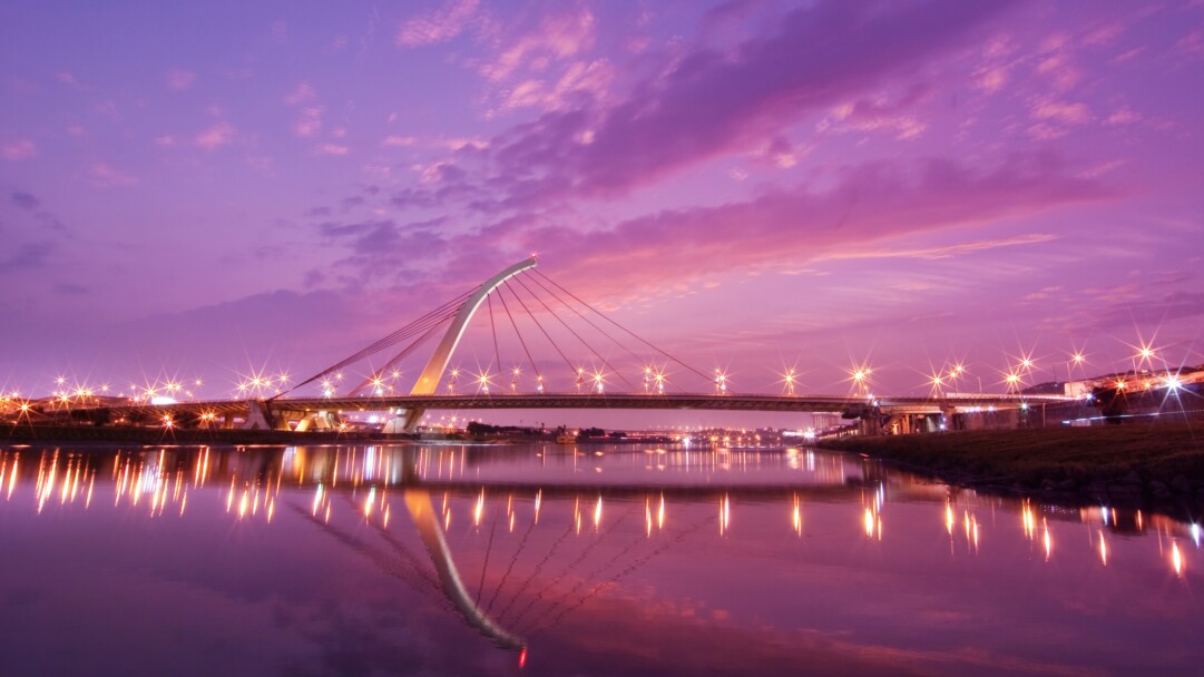 Experience the beauty of Taiwan's Dazhi Bridge with this stunning 4K wallpaper. This landscape scenery wallpaper features the majestic bridge amidst a picturesque cityscape and a tranquil river.