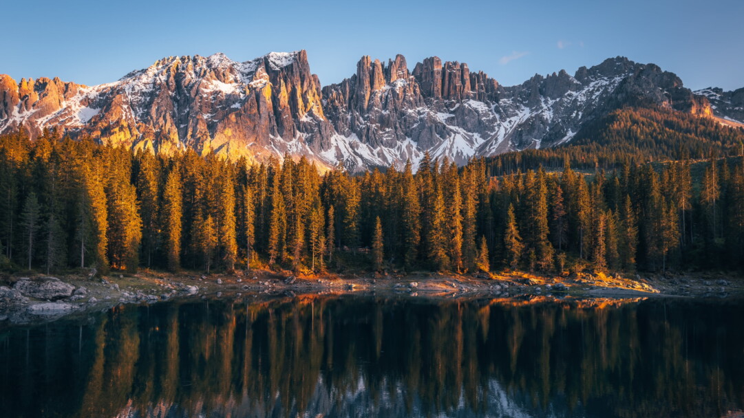 Immerse yourself in the serene beauty of Karersee Lake in Italy's Dolomites with this mesmerizing 4K wallpaper. The alpine lake, surrounded by the stunning landscape of South Tyrol, offers a tranquil and scenic escape. Perfect for travelers and those seeking a desktop background that captures the natural tranquility and alpine wonder of this Italian gem.
