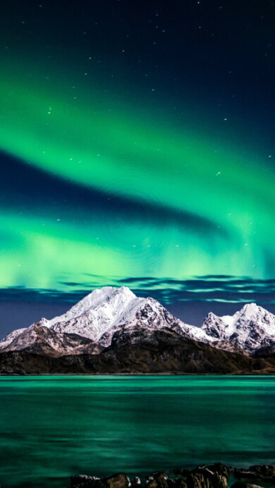 Behold the breathtaking beauty of the Northern Lights dancing above majestic mountains in this stunning 4K wallpaper. Experience the magic of the aurora borealis against the backdrop of a serene night sky. Perfect for nature enthusiasts and travelers seeking the celestial wonder of polar lights as a captivating desktop background.