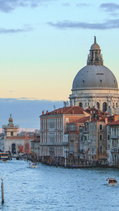 A breathtaking 4K wallpaper captures the enchanting beauty of the Grand Canal at sunset in Venice, Italy. The golden hues of the setting sun cast a warm glow over the tranquil water, illuminating the historic architecture and creating stunning reflections. Ideal for adding a touch of elegance to your desktop or mobile screen.