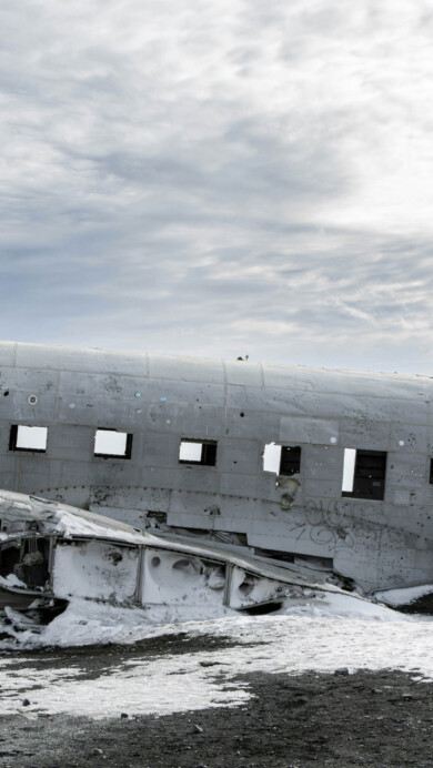 A breathtaking 4K wallpaper captures the Solheimasandur plane wreck amidst a winter landscape. The abandoned airplane lies frozen in time, surrounded by pristine snow and icy terrain, creating a dramatic and atmospheric scene. Perfect for adorning your desktop or mobile screen with a stunning winter vista.