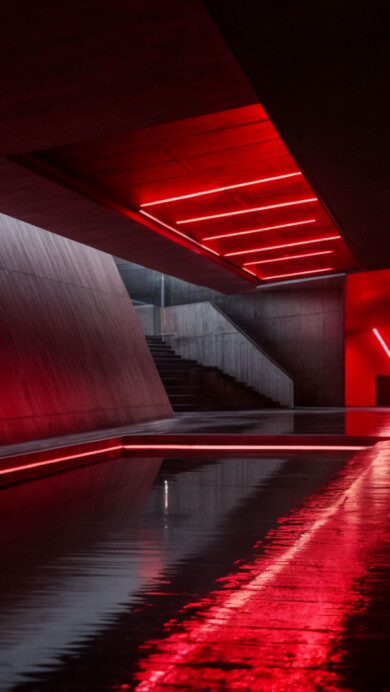 A striking 4K wallpaper featuring a red neon-lit hallway that leads into an illuminated, futuristic space. The bold, glowing lights create a vibrant atmosphere, making it the perfect backdrop for any desktop or mobile screen.